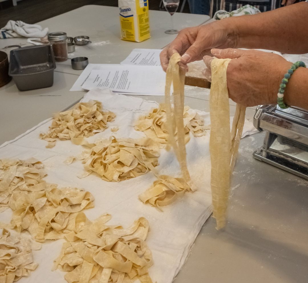 Person separating long strands of fresh pasta into separate piles